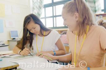 2 девочки работают вместе над английским заданием на уроке