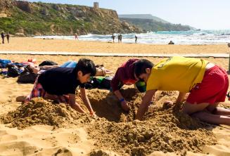 Групп-лидер и дети копают ямку на пляже