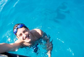 Студент купается рядом с яхтой в Комино